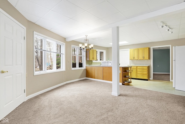 interior space featuring beamed ceiling, track lighting, baseboards, light colored carpet, and a chandelier