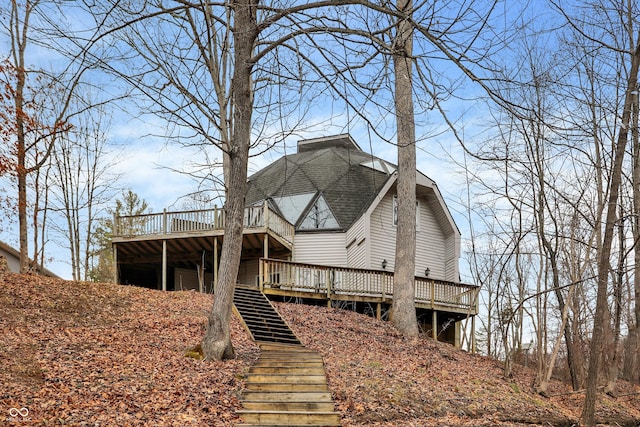 back of property with a deck, stairway, and a shingled roof