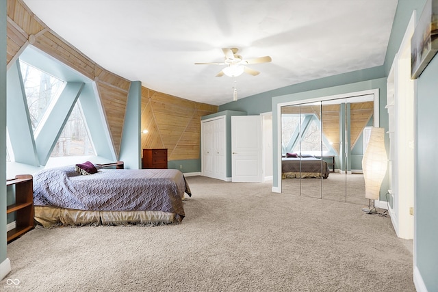 carpeted bedroom with wooden walls, a ceiling fan, baseboards, and two closets