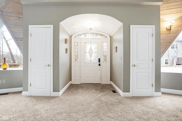 entrance foyer featuring carpet flooring, baseboards, and arched walkways