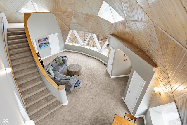 interior space featuring stairway, carpet flooring, baseboards, and high vaulted ceiling