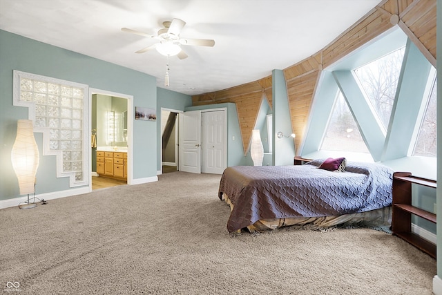 bedroom featuring carpet, baseboards, ceiling fan, ensuite bathroom, and wood walls