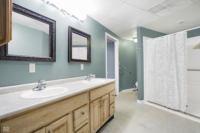 bathroom featuring a sink, visible vents, a drop ceiling, and double vanity