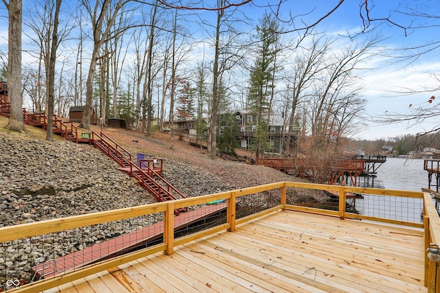 wooden deck with stairs, a dock, and a water view