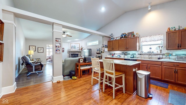 kitchen featuring a center island, ceiling fan, a breakfast bar area, lofted ceiling, and decorative backsplash