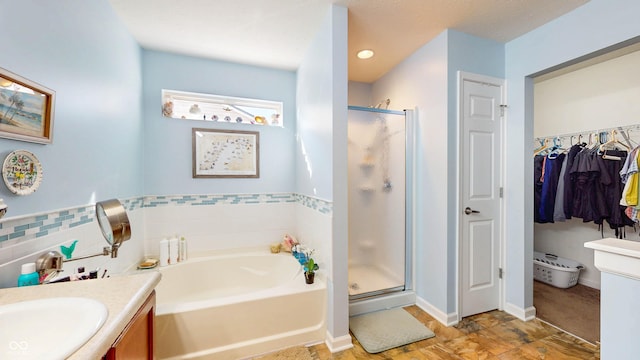 bathroom with a bath, a stall shower, vanity, and a walk in closet