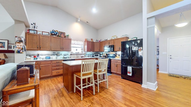 kitchen featuring light wood-style floors, a kitchen island, black appliances, and light countertops