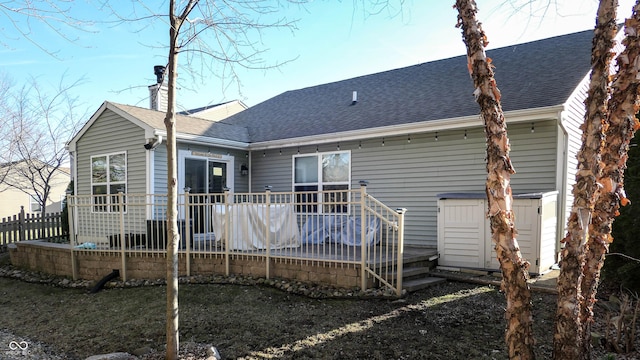 rear view of property with a wooden deck and roof with shingles