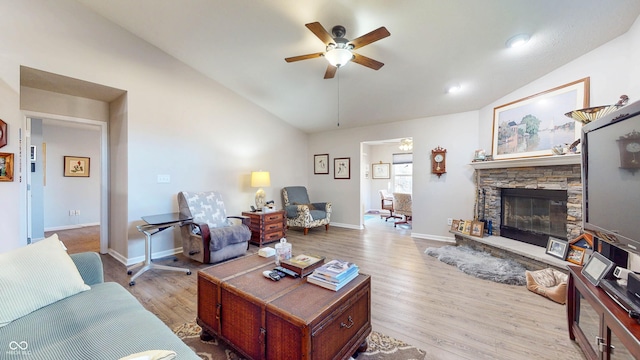 living room with a stone fireplace, baseboards, ceiling fan, and wood finished floors