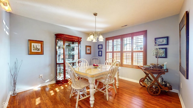 dining area with hardwood / wood-style floors, baseboards, visible vents, and a chandelier