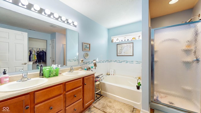 bathroom featuring double vanity, a bath, a stall shower, and a sink