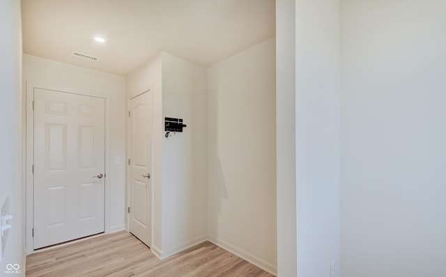 corridor featuring visible vents, baseboards, and light wood-style floors