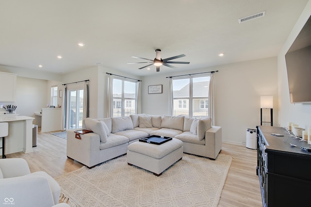 living area with visible vents, a healthy amount of sunlight, light wood-type flooring, and ceiling fan