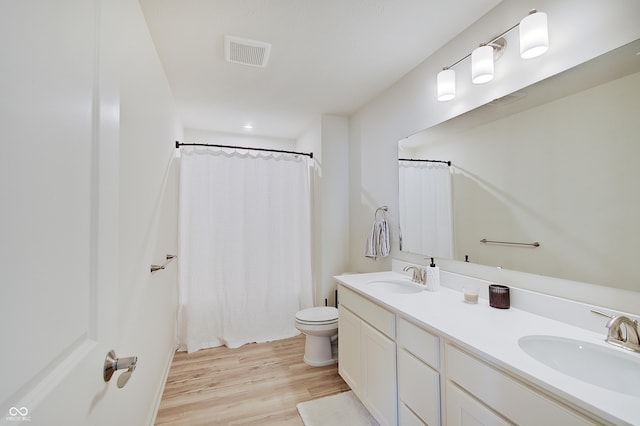 full bathroom featuring a sink, visible vents, toilet, and wood finished floors