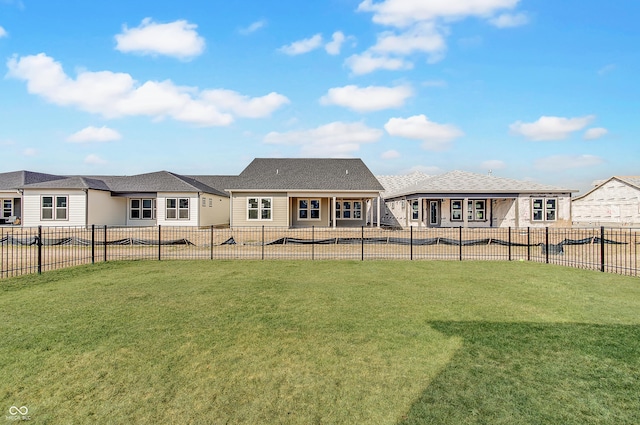 rear view of property featuring a lawn, a patio, a shingled roof, and a fenced backyard