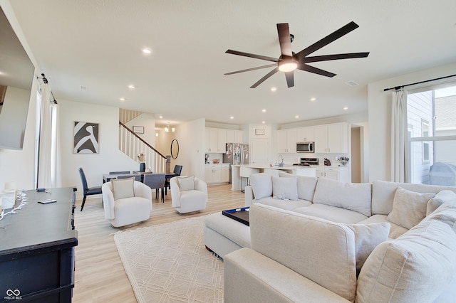 living room with stairway, recessed lighting, light wood-style flooring, and ceiling fan