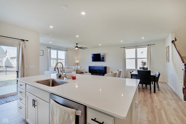 kitchen featuring a center island with sink, a sink, open floor plan, dishwasher, and ceiling fan