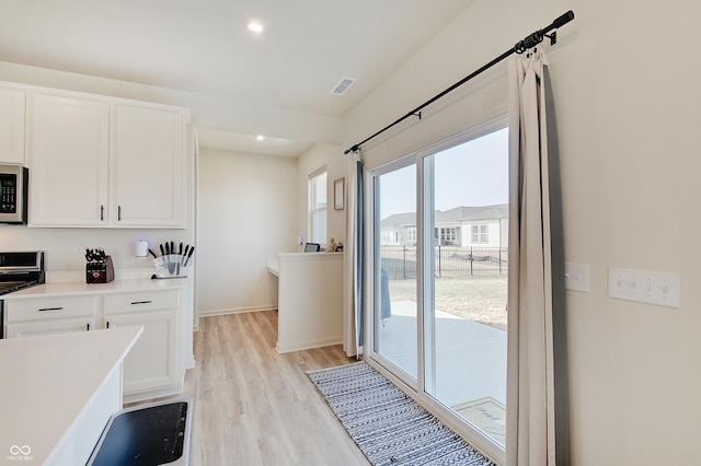 kitchen featuring recessed lighting, stainless steel appliances, light countertops, white cabinetry, and light wood-type flooring