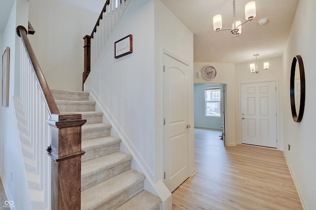 stairway with baseboards, wood finished floors, and a chandelier