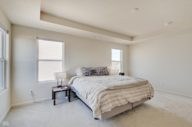 bedroom with carpet flooring, a tray ceiling, and baseboards