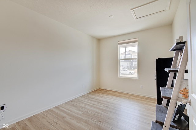 interior space featuring attic access, light wood-style floors, and baseboards