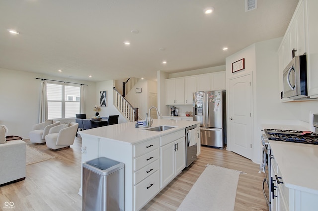 kitchen with open floor plan, light countertops, light wood-style flooring, appliances with stainless steel finishes, and a sink