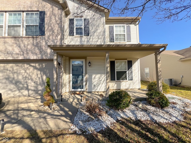 view of front of house featuring a porch, cooling unit, concrete driveway, and an attached garage