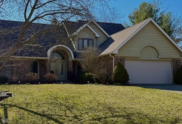 view of front of home with a front yard, a garage, brick siding, and driveway