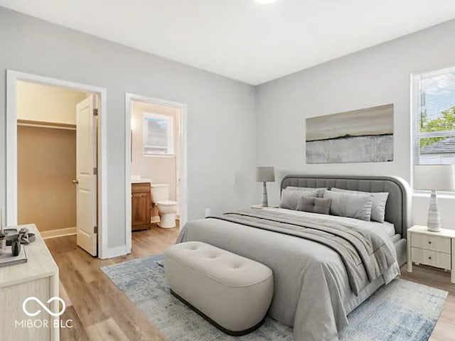 bedroom with a spacious closet, light wood-style flooring, and connected bathroom