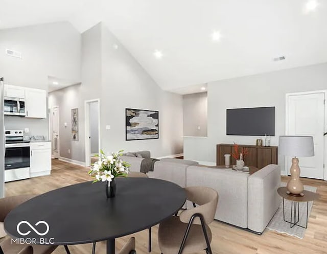 dining space featuring baseboards, visible vents, high vaulted ceiling, and light wood-style floors