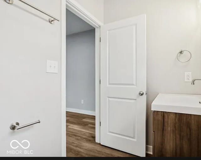 bathroom featuring vanity, wood finished floors, and baseboards