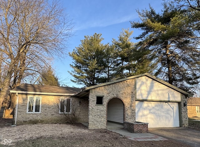 view of front facade featuring aphalt driveway, stone siding, and an attached garage