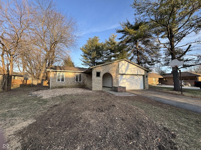 view of front of home featuring stone siding, an attached garage, and driveway