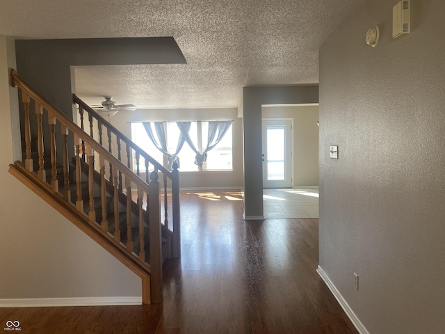 entryway with baseboards, a textured ceiling, wood finished floors, and stairs