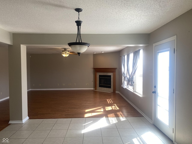 unfurnished living room with light tile patterned floors, a textured ceiling, and a tile fireplace