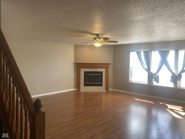 unfurnished living room with dark wood-style floors, baseboards, a fireplace, and stairs