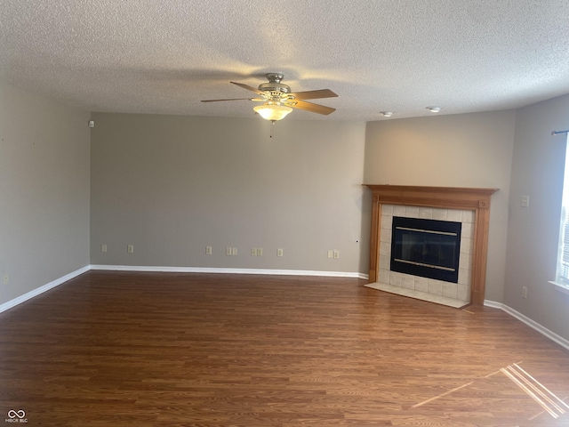 unfurnished living room with baseboards, wood finished floors, and a tiled fireplace