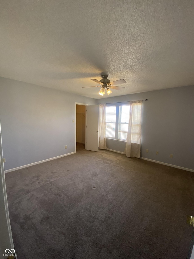 carpeted empty room with a textured ceiling, baseboards, and a ceiling fan