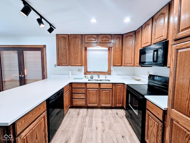 4109 E Epler Ave, Indianapolis, IN 46237 - kitchen with brown cabinetry, light wood-style flooring, a sink, black appliances, and light countertops