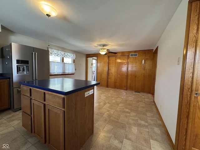 kitchen featuring dark countertops, visible vents, a kitchen island, high quality fridge, and brown cabinetry