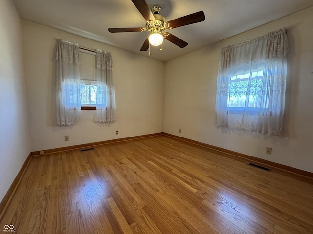 empty room with baseboards, visible vents, light wood finished floors, and ceiling fan