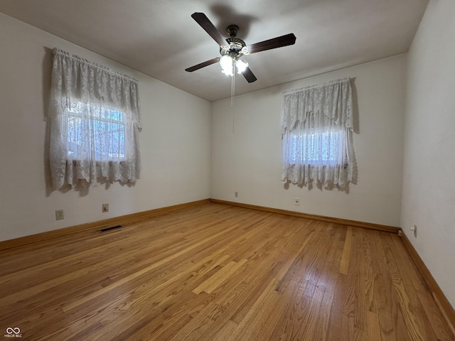 empty room with visible vents, a healthy amount of sunlight, baseboards, and light wood-style floors