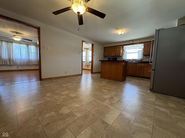 kitchen with a sink, dark countertops, open floor plan, and freestanding refrigerator