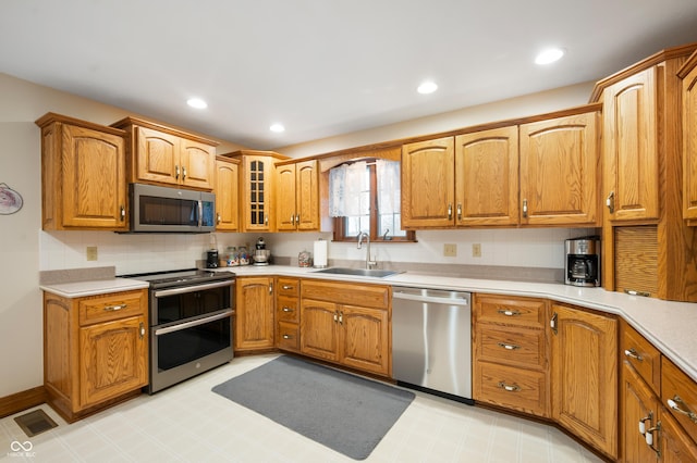 kitchen with light floors, appliances with stainless steel finishes, light countertops, and a sink