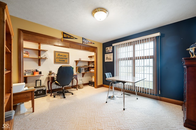 home office featuring carpet flooring, baseboards, and a textured ceiling