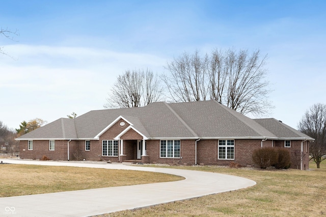 ranch-style home featuring a front yard, brick siding, driveway, and a shingled roof