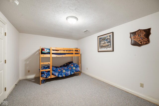 carpeted bedroom featuring baseboards, visible vents, and a textured ceiling