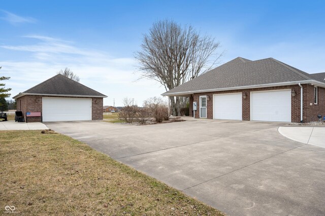 view of side of property featuring brick siding, a yard, a shingled roof, and a garage