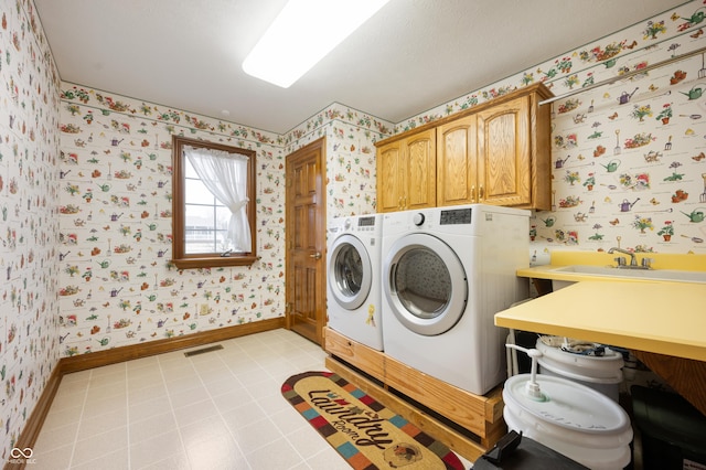 laundry room featuring wallpapered walls, baseboards, washing machine and dryer, cabinet space, and a sink