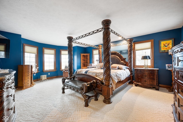 carpeted bedroom featuring multiple windows, a textured ceiling, and baseboards